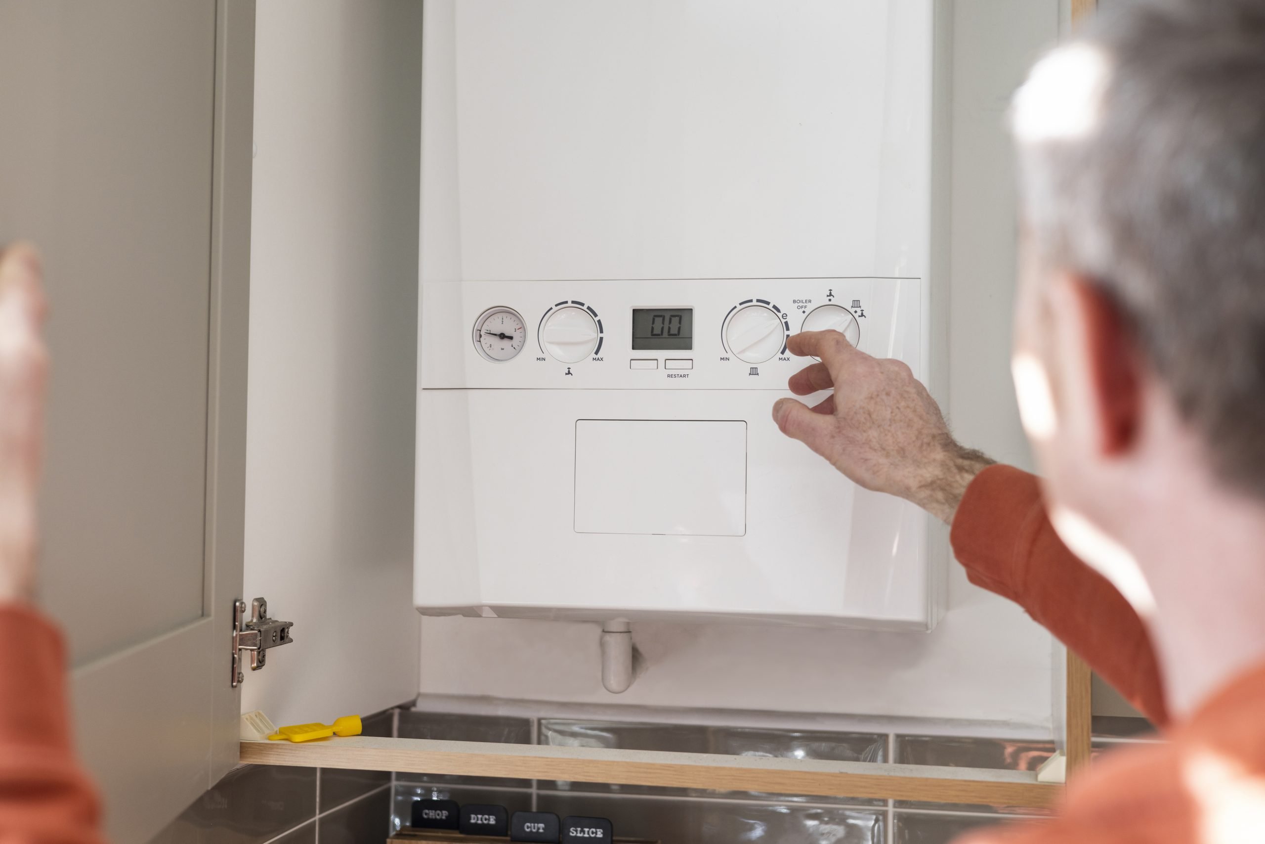 A person adjusting the controls on a domestic boiler