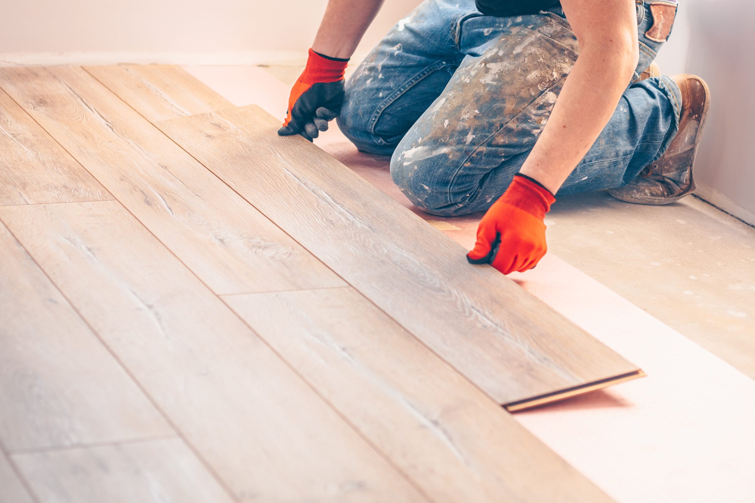 A tradesperson fitting laminate flooring during property maintenance